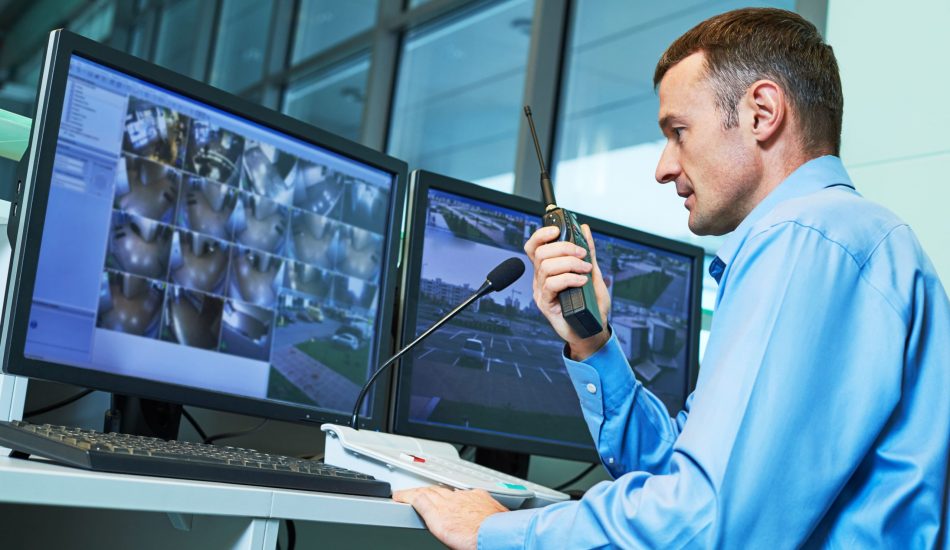 Security-guard-working-monitoring-screens-dual-monitors-systems-surveillance-scaled
